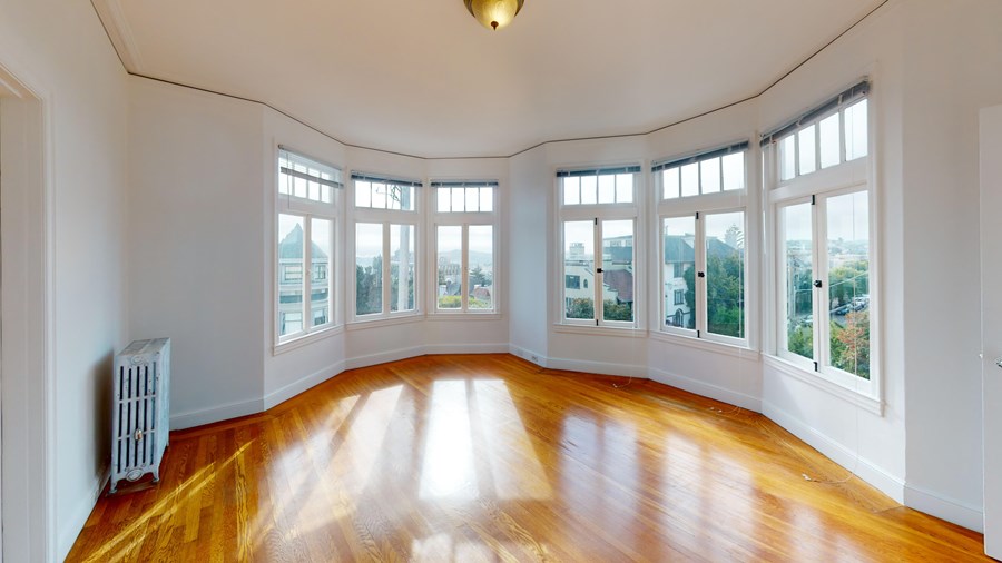 A room with wooden floors and white walls with a white radiator on the left side.